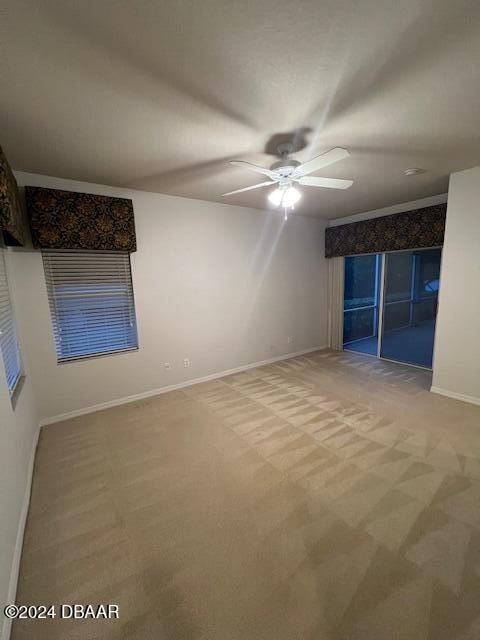 carpeted spare room featuring ceiling fan