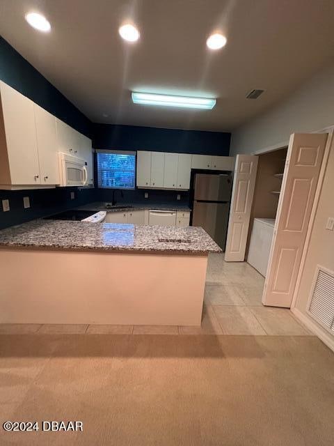 kitchen featuring kitchen peninsula, light carpet, white cabinets, and stainless steel refrigerator