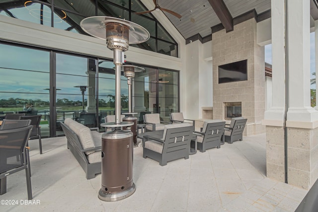 patio terrace at dusk with an outdoor stone fireplace and ceiling fan