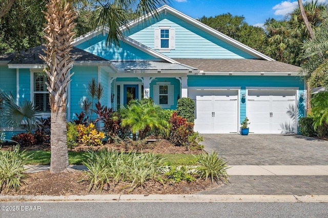 view of front of home with a garage, driveway, and a shingled roof