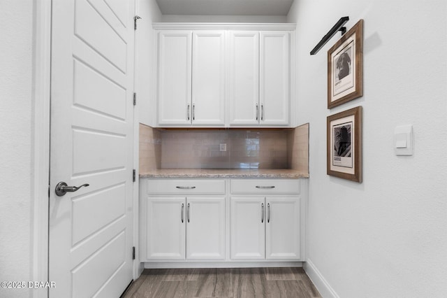 bar with baseboards, light wood-style flooring, and decorative backsplash