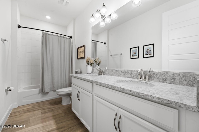 full bath featuring double vanity, visible vents, toilet, wood finished floors, and a sink