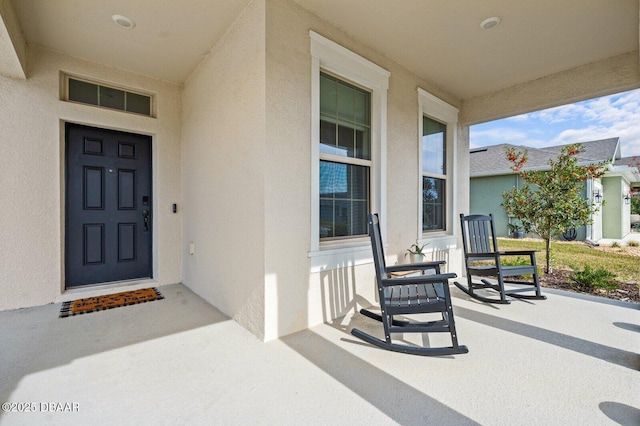 entrance to property featuring covered porch and stucco siding