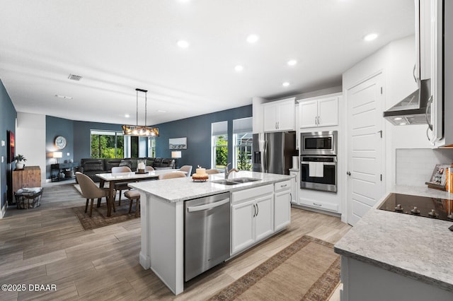 kitchen featuring a sink, visible vents, open floor plan, appliances with stainless steel finishes, and an island with sink