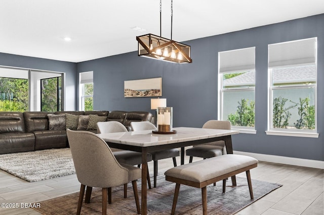 dining room featuring a chandelier, light wood-style flooring, and baseboards