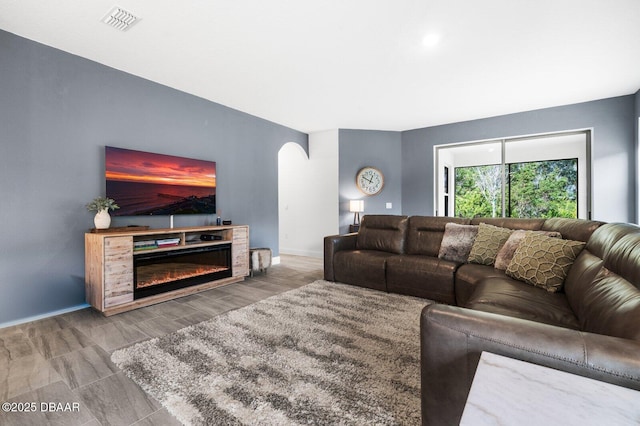 living area featuring a glass covered fireplace, visible vents, and baseboards