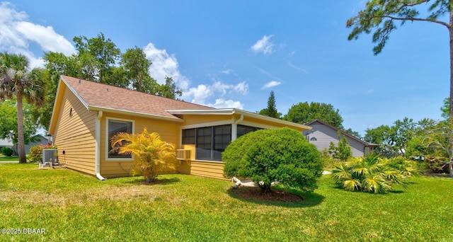 back of house featuring central AC unit, a sunroom, and a lawn