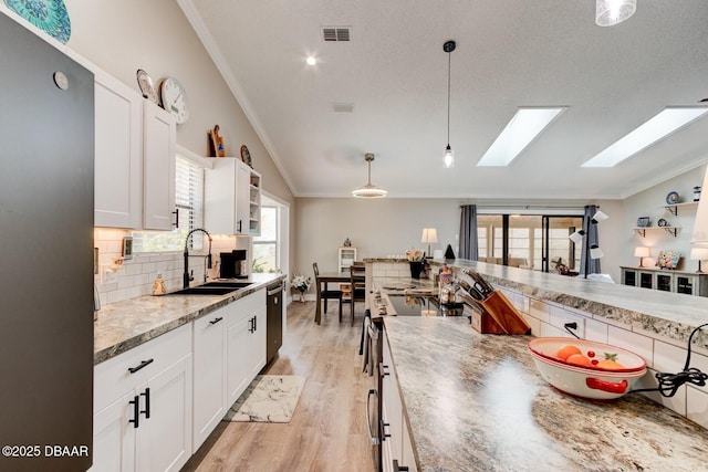 kitchen with a sink, crown molding, lofted ceiling with skylight, and appliances with stainless steel finishes