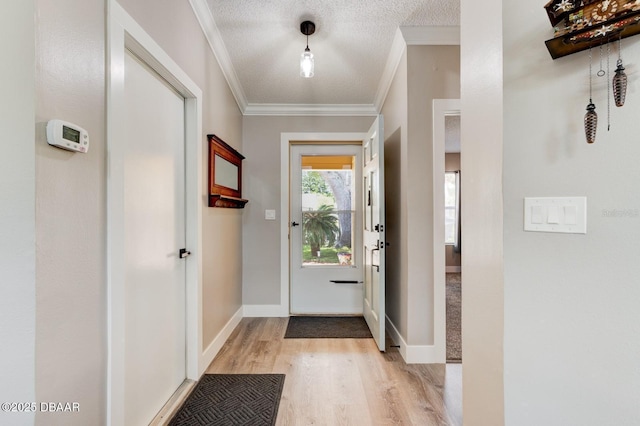 doorway to outside featuring light wood-type flooring, ornamental molding, and a textured ceiling