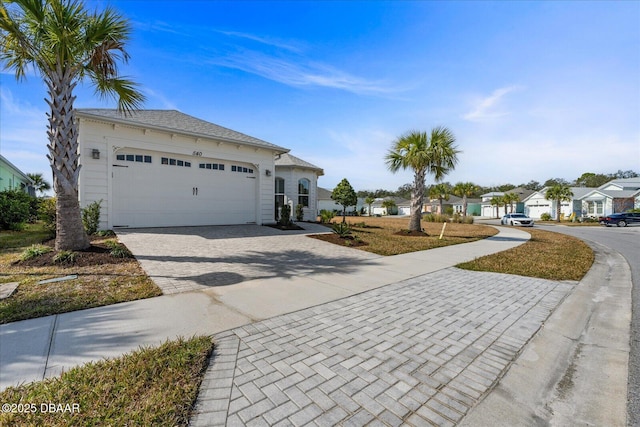 exterior space with decorative driveway, an attached garage, and a residential view