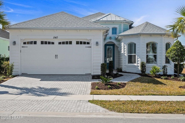 view of front of home featuring a garage, decorative driveway, and roof with shingles