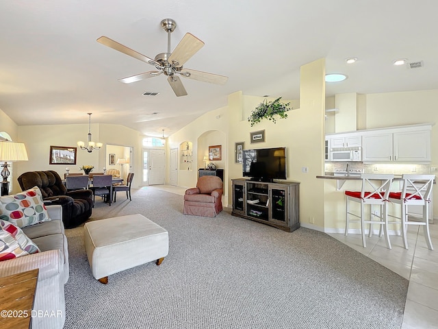 living room featuring ceiling fan with notable chandelier, light colored carpet, and lofted ceiling