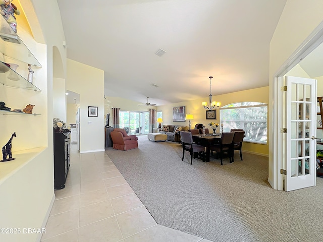 carpeted dining area featuring ceiling fan with notable chandelier and lofted ceiling