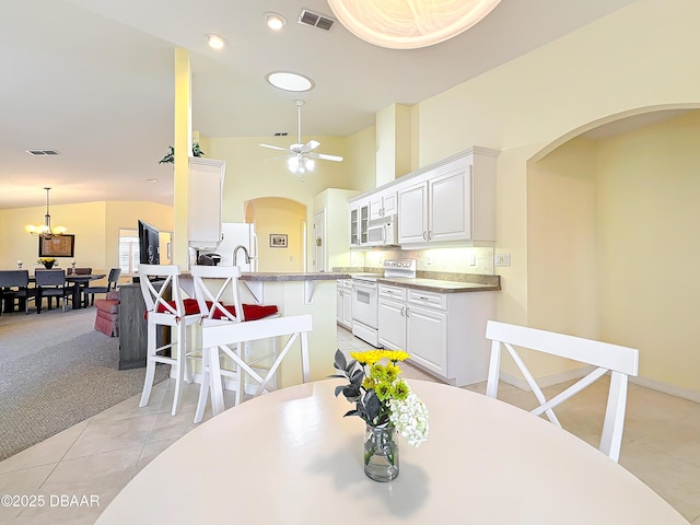 dining room with lofted ceiling, light carpet, and ceiling fan with notable chandelier