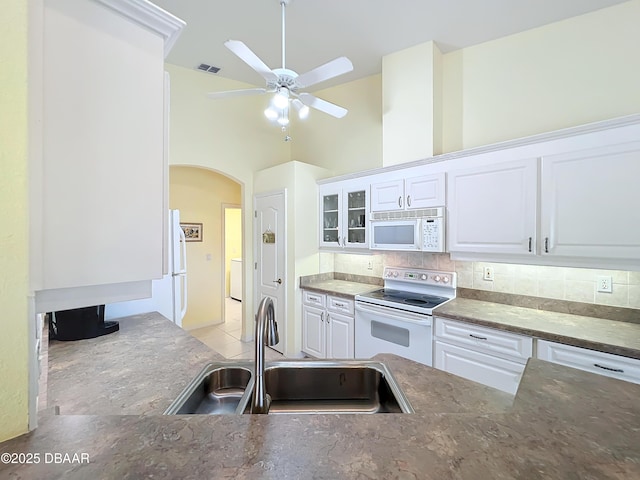 kitchen featuring white appliances, backsplash, white cabinetry, and sink