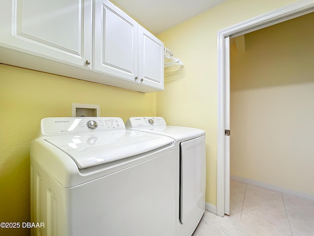 laundry area with cabinets, light tile patterned floors, and washer and clothes dryer