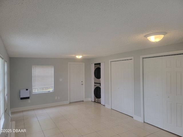 interior space featuring heating unit, multiple windows, stacked washing maching and dryer, and two closets