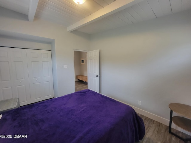 bedroom featuring a closet, wood finished floors, wooden ceiling, beamed ceiling, and baseboards