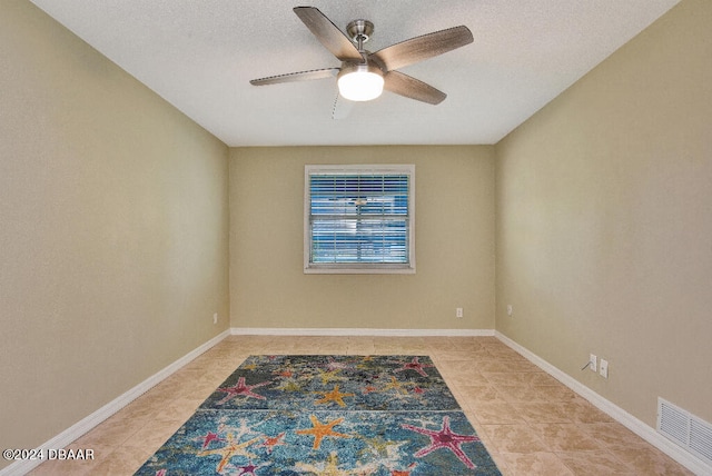 tiled empty room featuring ceiling fan and a textured ceiling