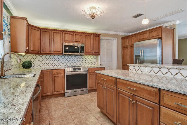 kitchen featuring sink, light stone counters, appliances with stainless steel finishes, and ornamental molding