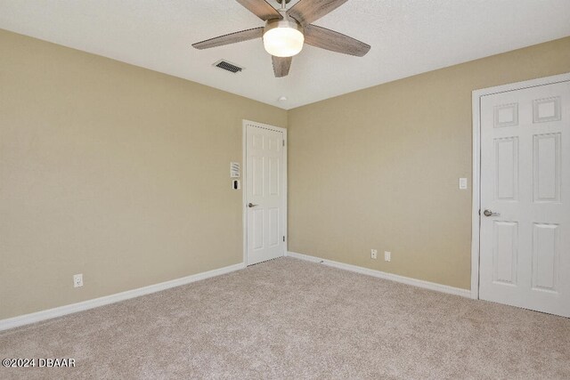 spare room featuring light colored carpet and ceiling fan