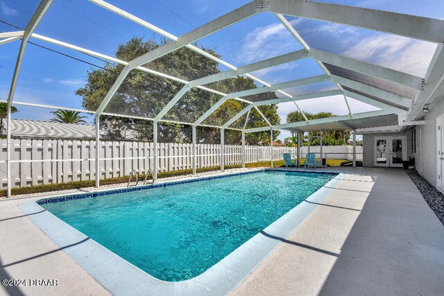 view of swimming pool with glass enclosure and a patio