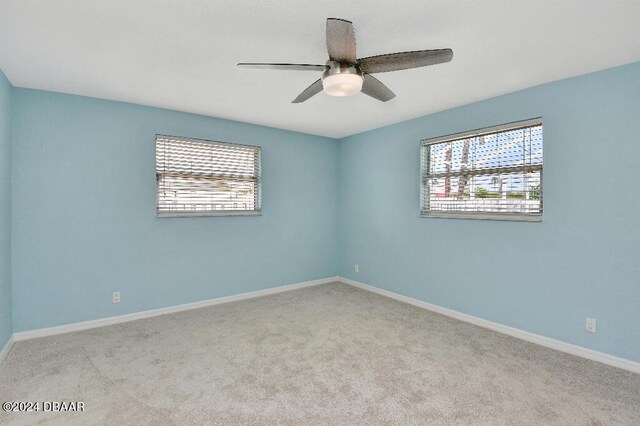 carpeted spare room featuring ceiling fan and a healthy amount of sunlight