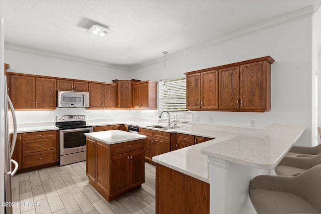 kitchen featuring crown molding, stainless steel appliances, a kitchen island, sink, and a breakfast bar area