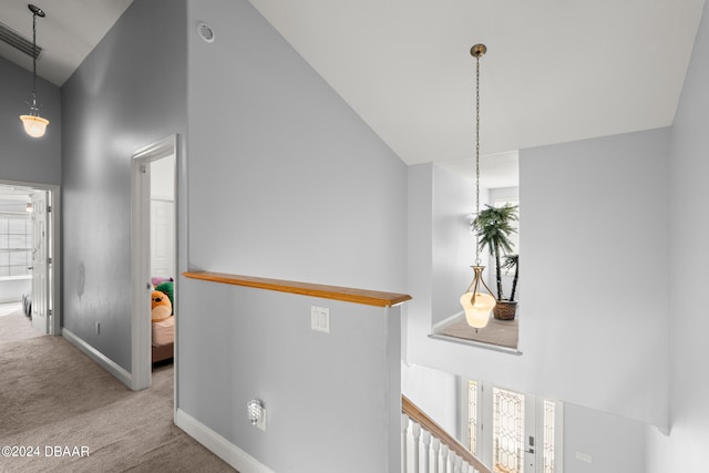 hallway with light carpet and high vaulted ceiling