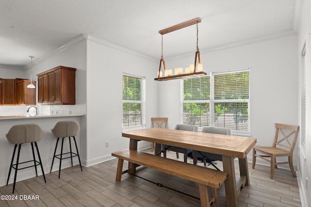 dining area with a wealth of natural light, a chandelier, light hardwood / wood-style floors, and ornamental molding