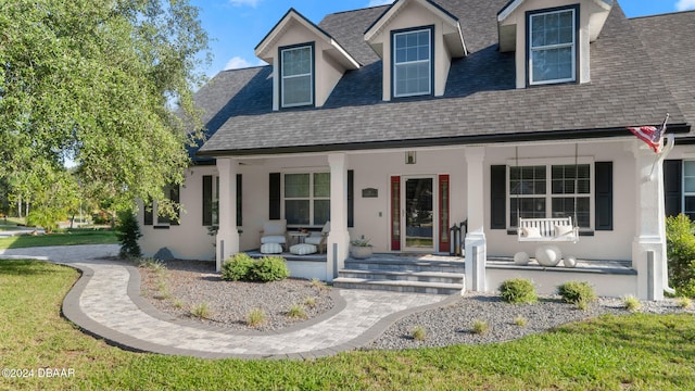 cape cod home with a front yard and covered porch