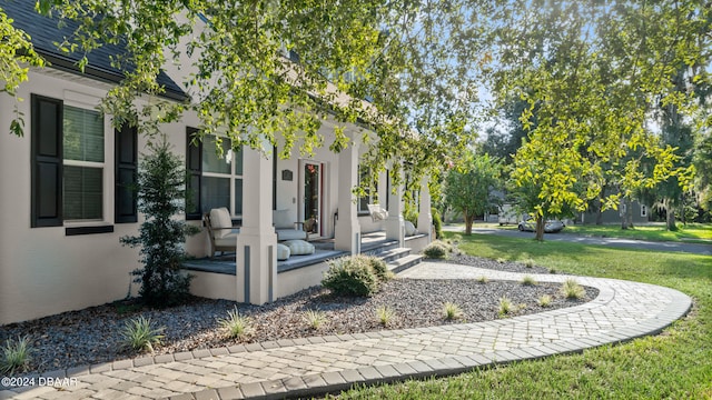 entrance to property featuring covered porch and a yard