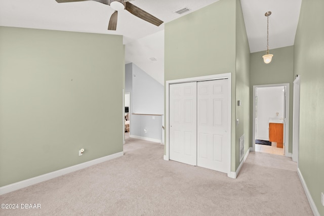 unfurnished bedroom with ceiling fan, light colored carpet, a closet, and high vaulted ceiling