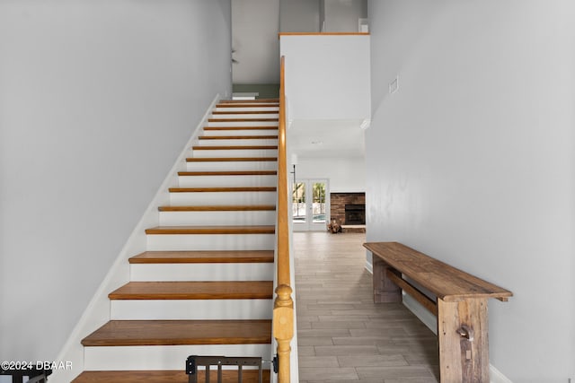 staircase featuring a stone fireplace and hardwood / wood-style flooring