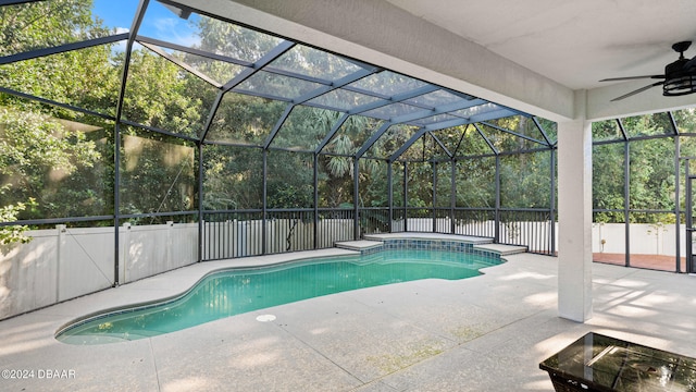 view of swimming pool with a patio, ceiling fan, and glass enclosure