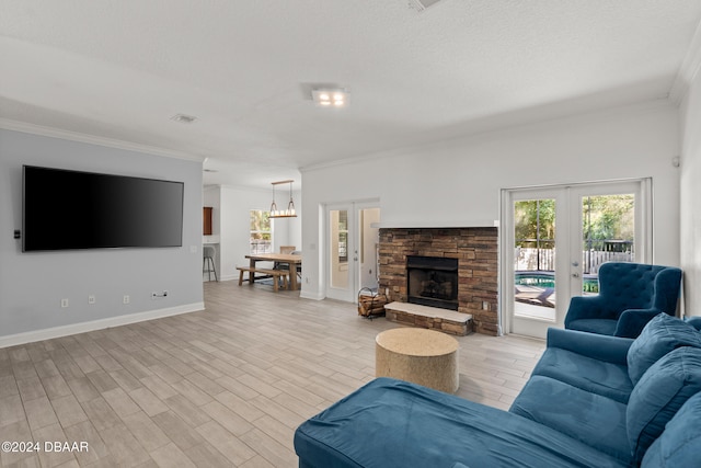 living room with french doors, light wood-type flooring, ornamental molding, and a stone fireplace