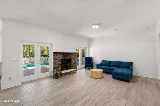 living room featuring ornamental molding, french doors, light hardwood / wood-style flooring, and a fireplace