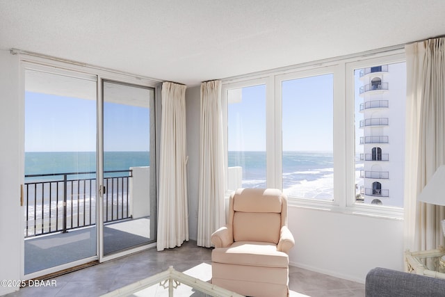 living area featuring a healthy amount of sunlight, a water view, and a textured ceiling