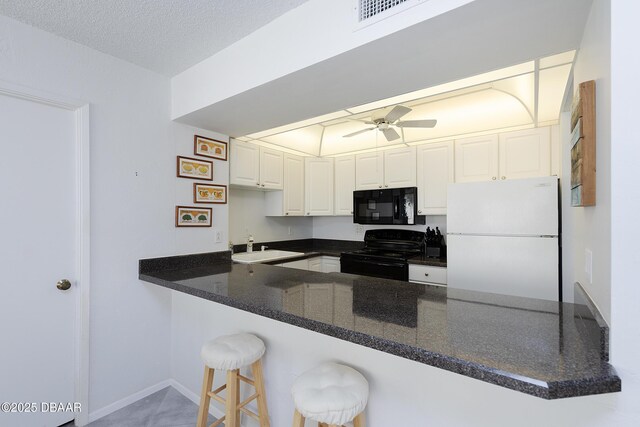 kitchen with a peninsula, black appliances, ceiling fan, and visible vents