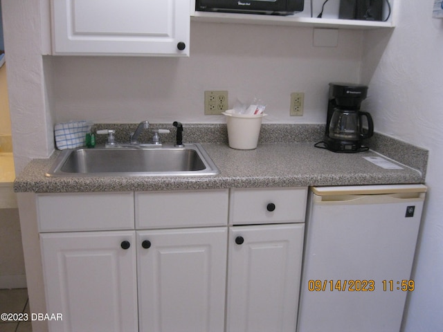 kitchen with dishwasher, white cabinetry, and sink