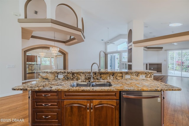 kitchen with light hardwood / wood-style floors, a kitchen island with sink, dishwasher, and sink