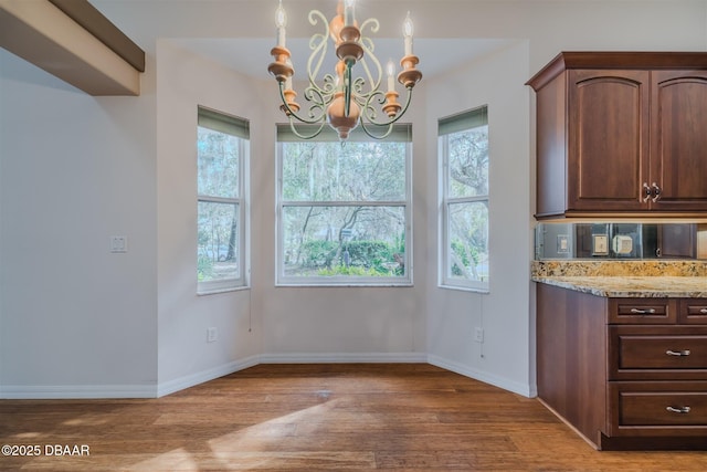 unfurnished dining area with a notable chandelier, wood-type flooring, and plenty of natural light