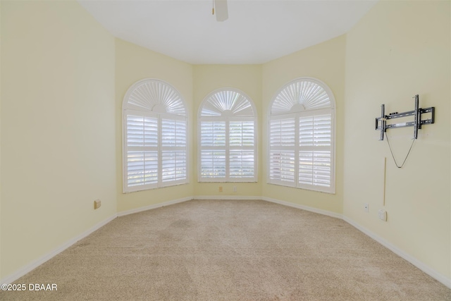 spare room with a healthy amount of sunlight, light colored carpet, and ceiling fan