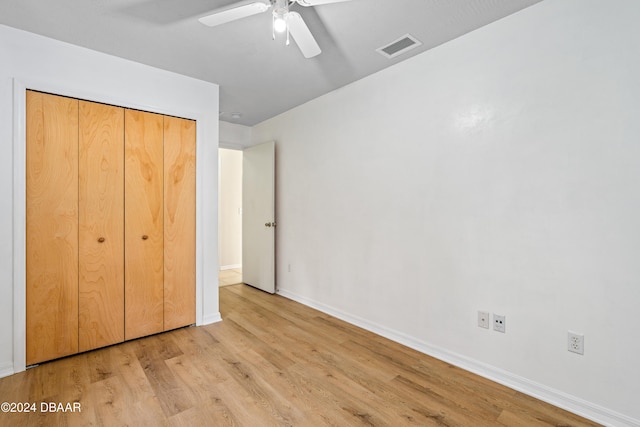 unfurnished bedroom with light hardwood / wood-style floors, ceiling fan, and a closet