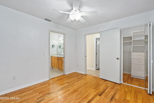 unfurnished bedroom with a closet, a spacious closet, light hardwood / wood-style flooring, ceiling fan, and ensuite bathroom