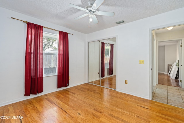 unfurnished bedroom with a closet, wood-type flooring, ceiling fan, and a textured ceiling