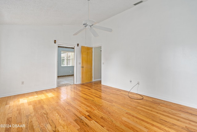 empty room featuring light wood-type flooring, a textured ceiling, ceiling fan, and high vaulted ceiling