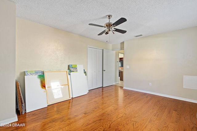 interior space featuring hardwood / wood-style flooring, ceiling fan, and a textured ceiling