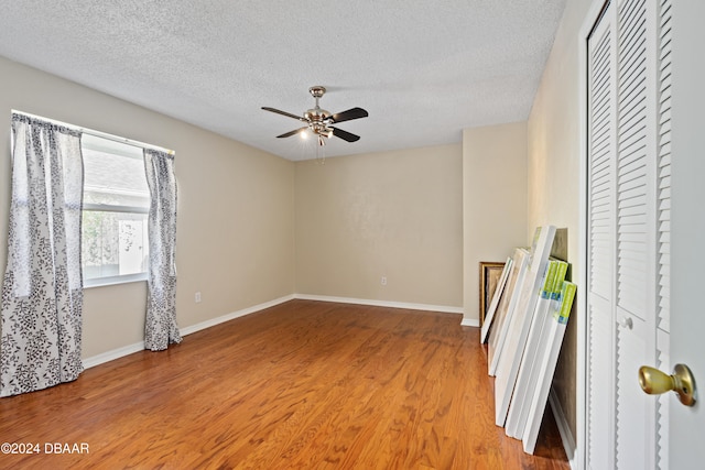 empty room featuring a textured ceiling, wood-type flooring, and ceiling fan