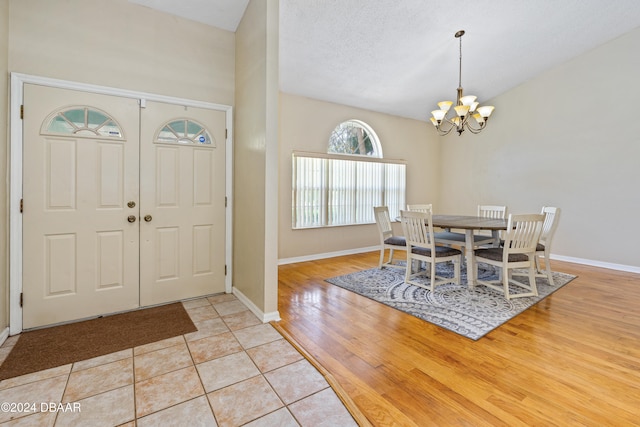 foyer entrance featuring a textured ceiling, a notable chandelier, and light hardwood / wood-style flooring